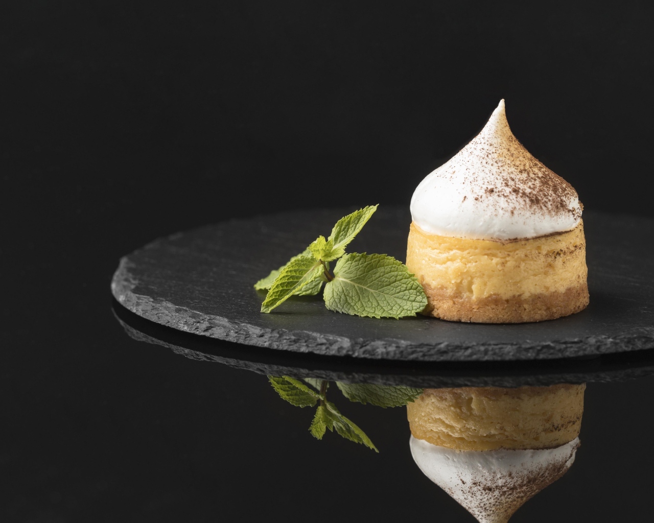 Десерт с кремом и листьями мяты на черном фоне