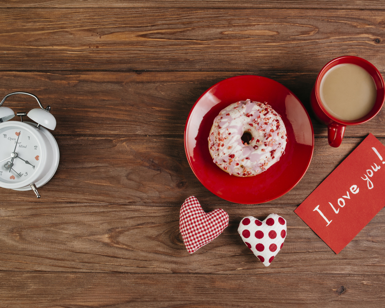 Пончик на столе с будильником, чашкой кофе и сердечками