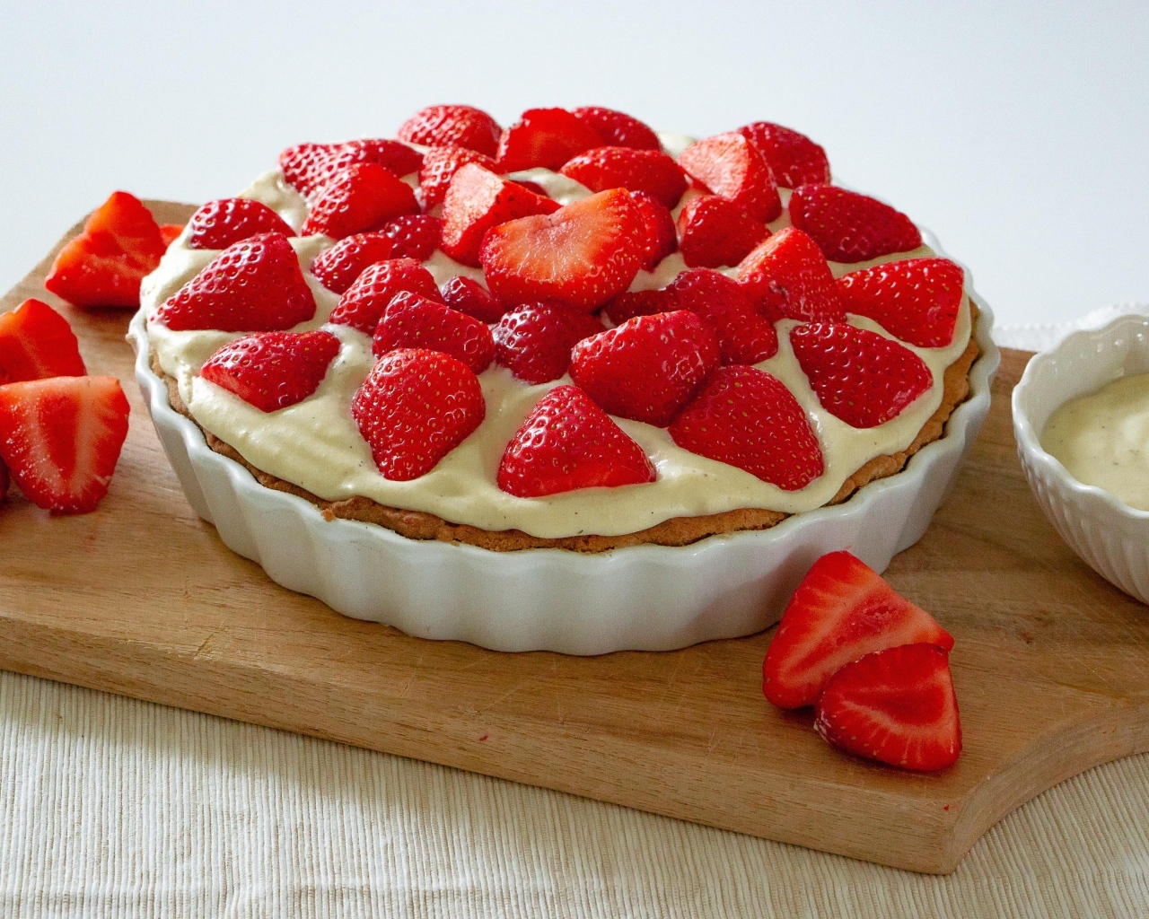 Большой пирог с кремом и ягодами спелой клубники на столе