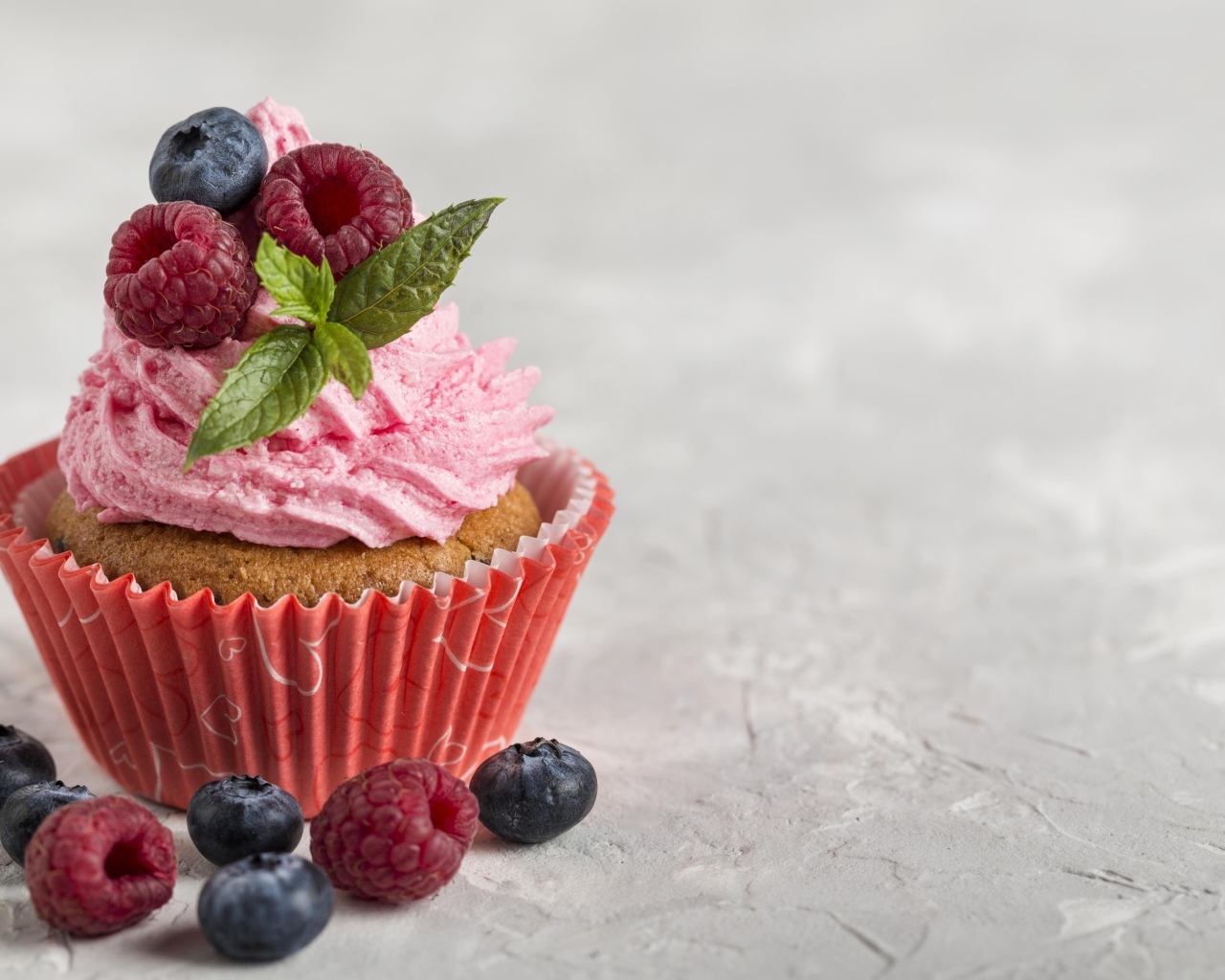 Маффин с розовым кремом и ягодами на столе