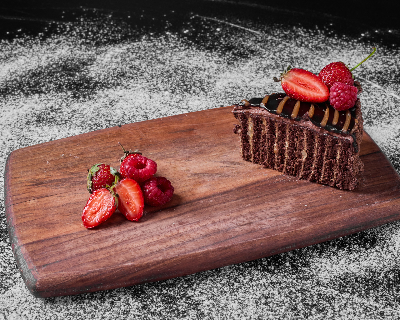 Кусок торта брауни с ягодами на доске
