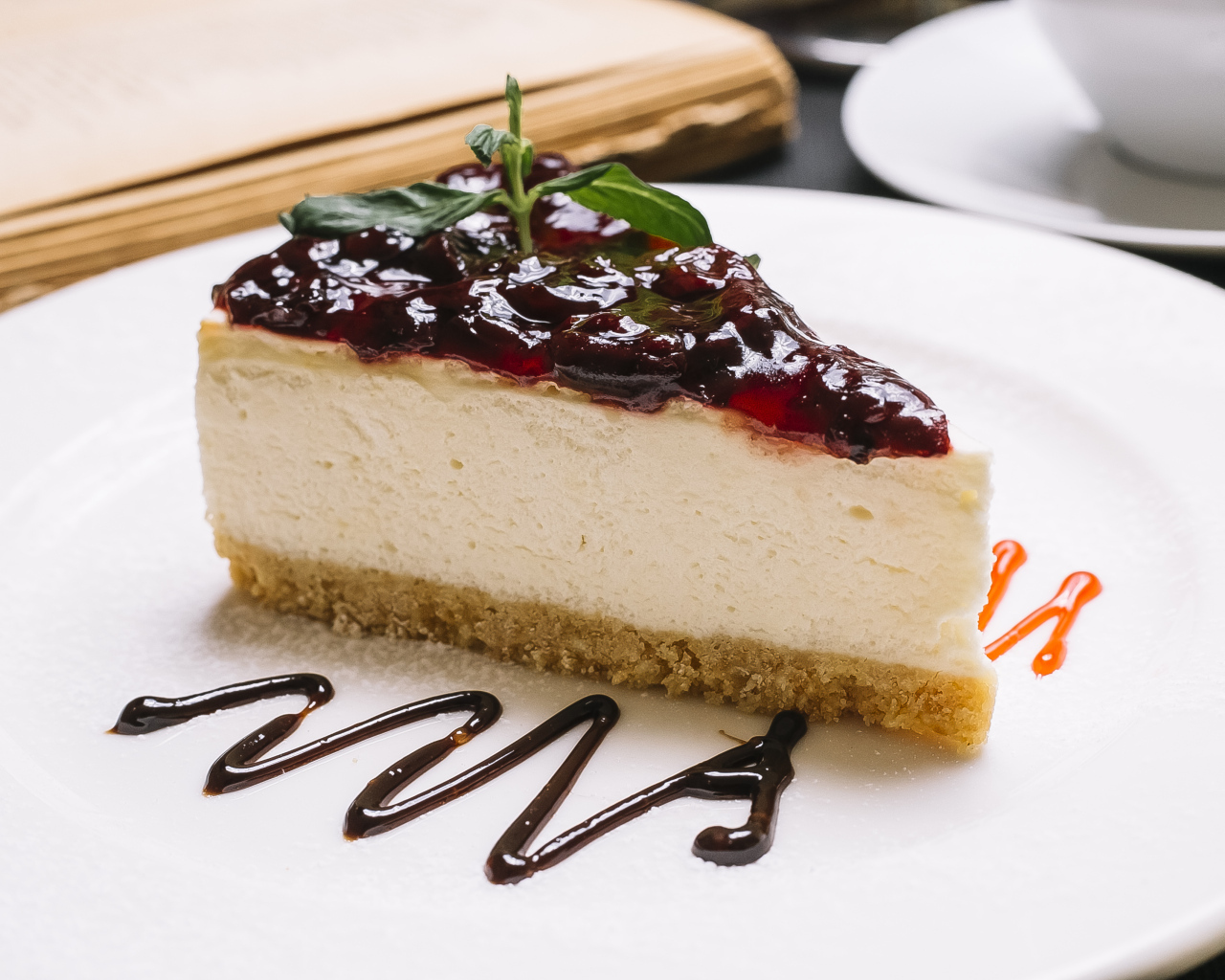 Кусок чизкейка с джемом на белой тарелке