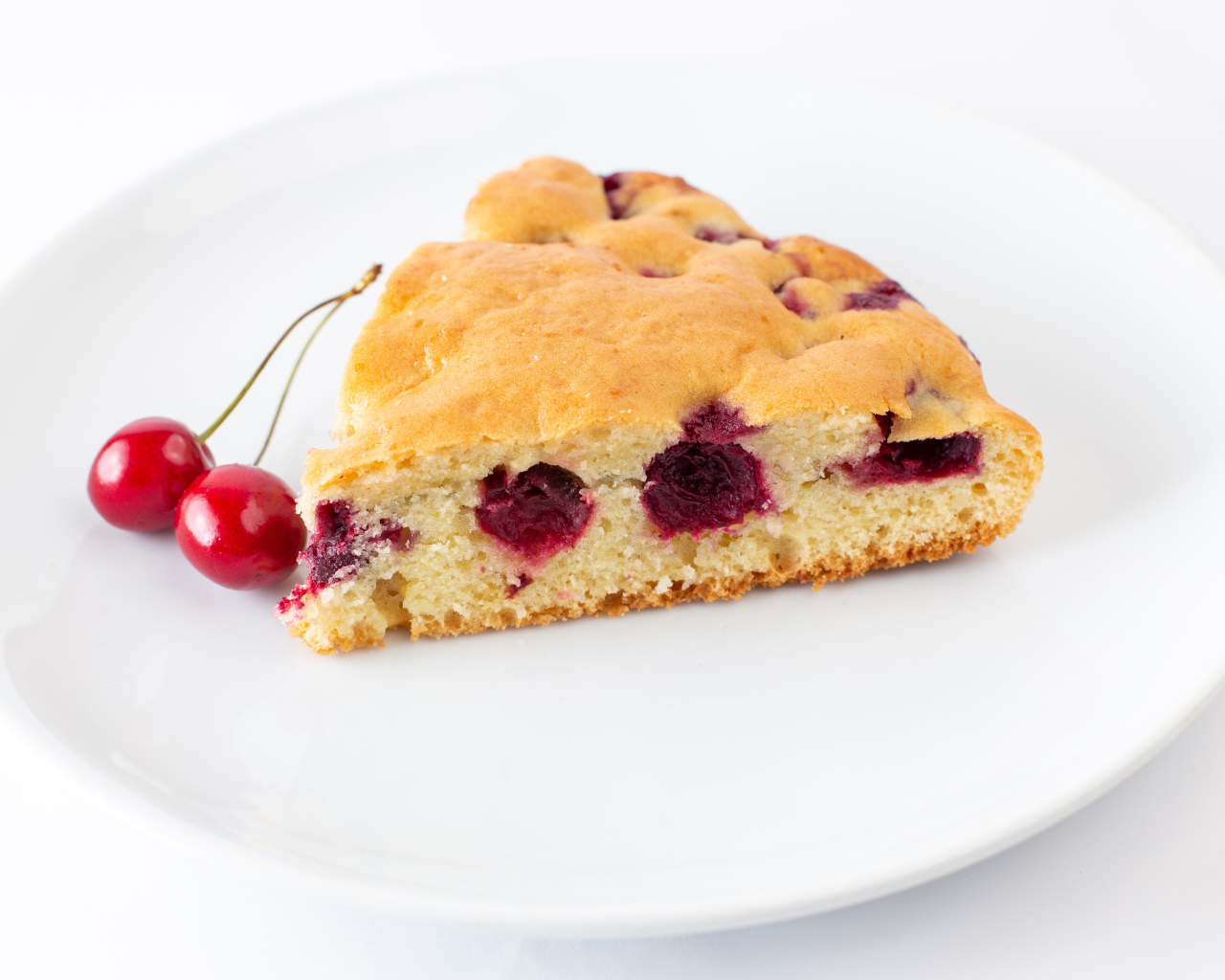 Кусок вишневого пирога с ягодами на тарелке