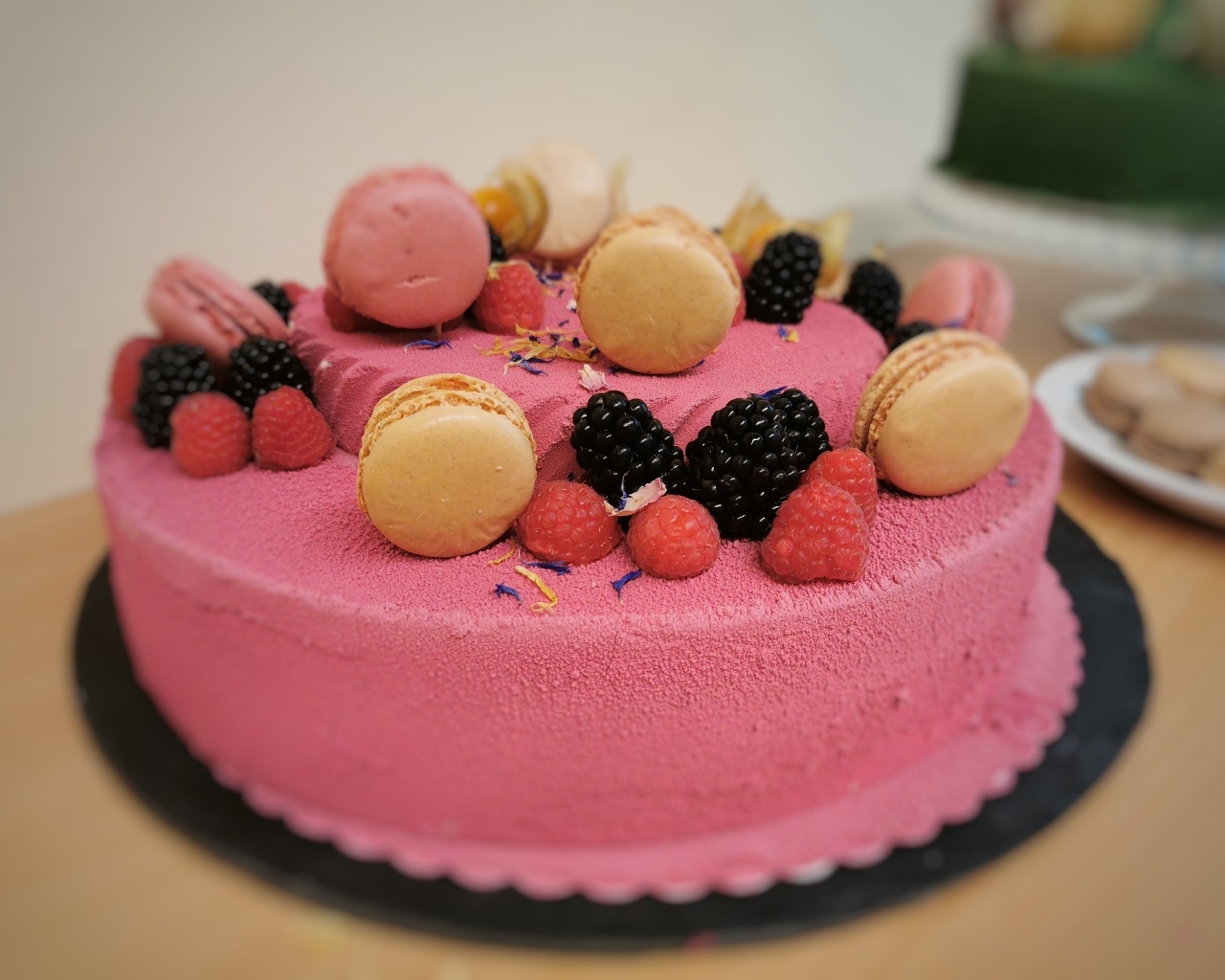 Розовый торт украшен печеньем и ягодами