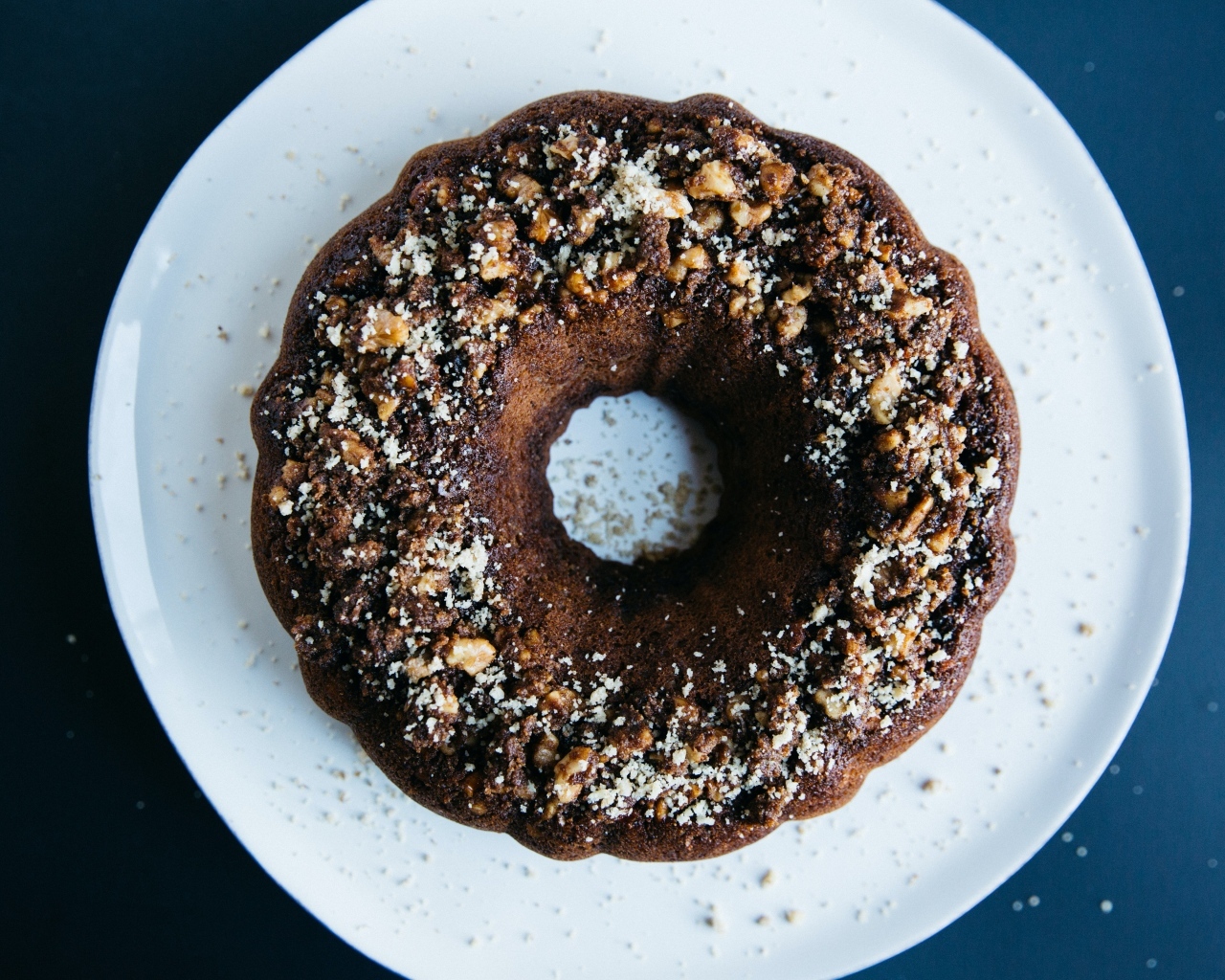 Круглый шоколадный кекс на большой белой тарелке