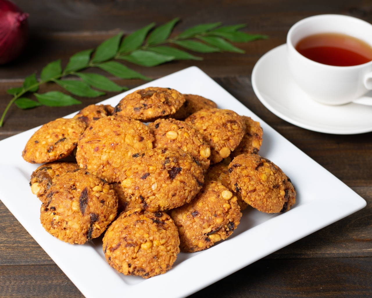 Сладкое печенье на большой белой тарелке на столе с чаем