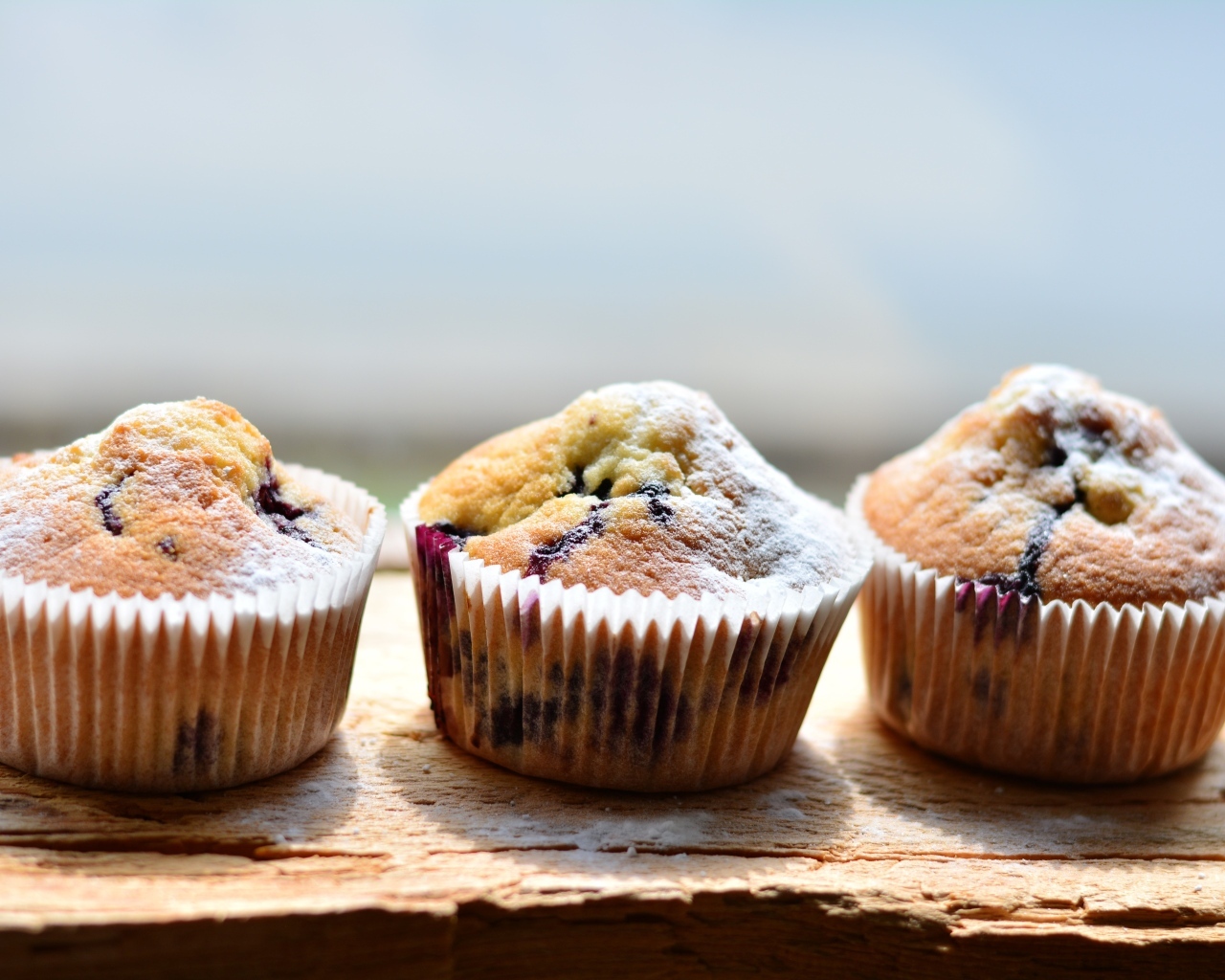 Три вкусных сладких кекса с сахарной пудрой на столе