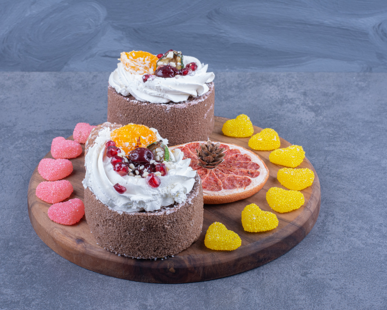 Два пирожных на деревянной доске с мармеладными конфетами