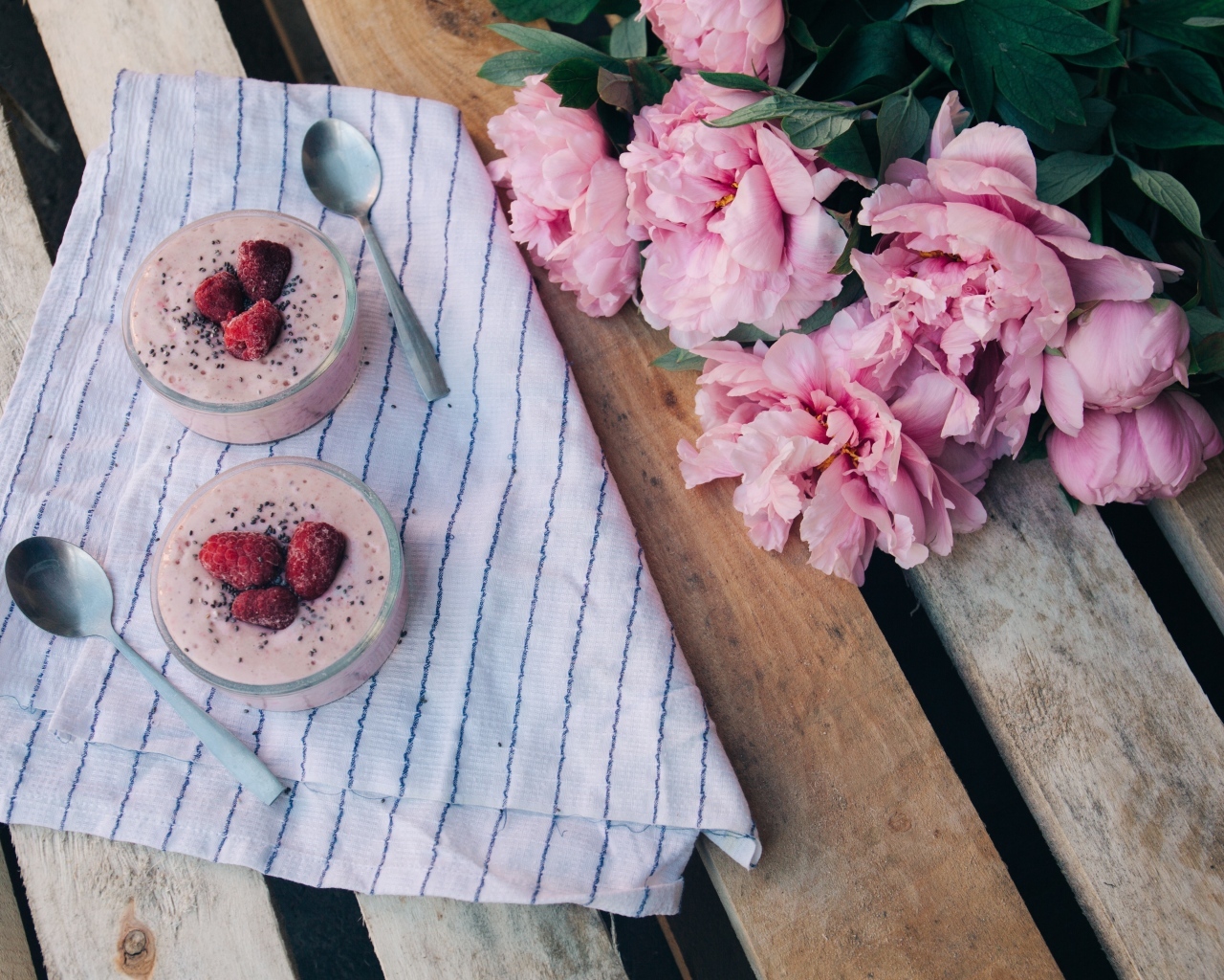 Два стакана с десертом на лавке с букетом пионов