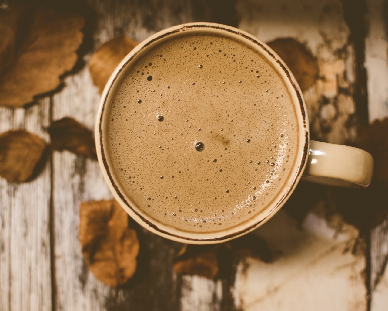 Чашка ароматного кофе с пенкой на столе с листьями