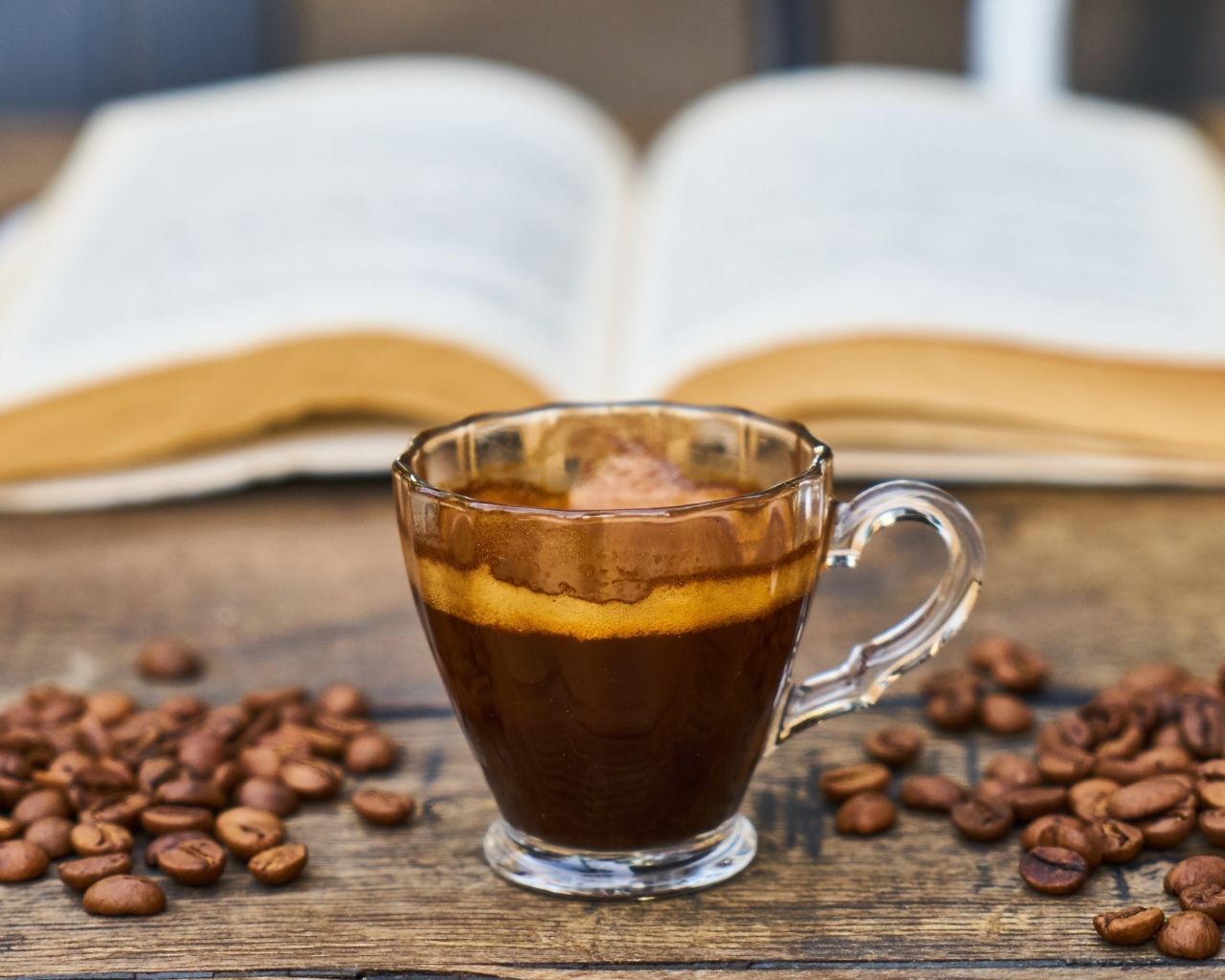 Чашка кофе на столе с зернами и книгой