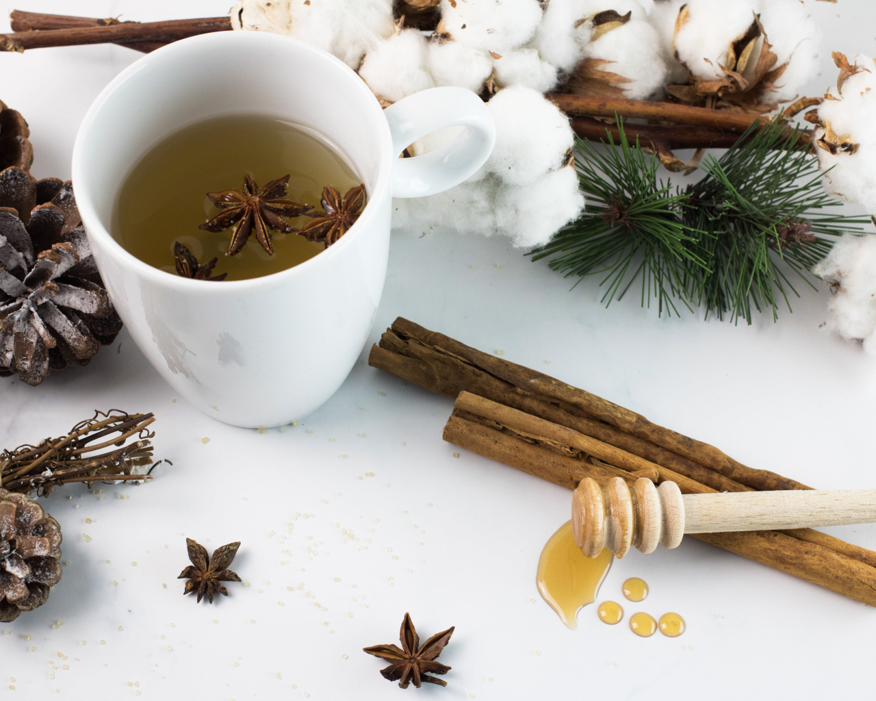 Чашка чая со специями на столе с хлопком и шишками