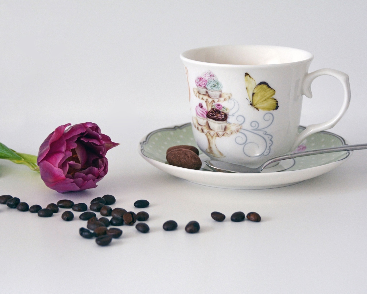 Чашка на столе с кофейными зернами и тюльпаном