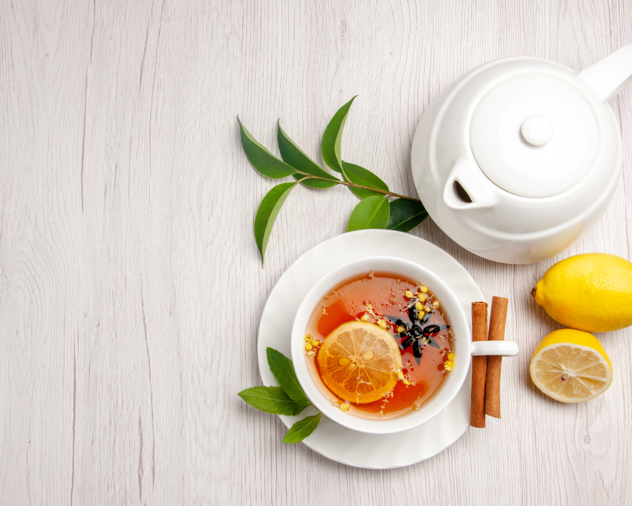 Вкусный чай в белой чашке на столе с лимоном и чайником