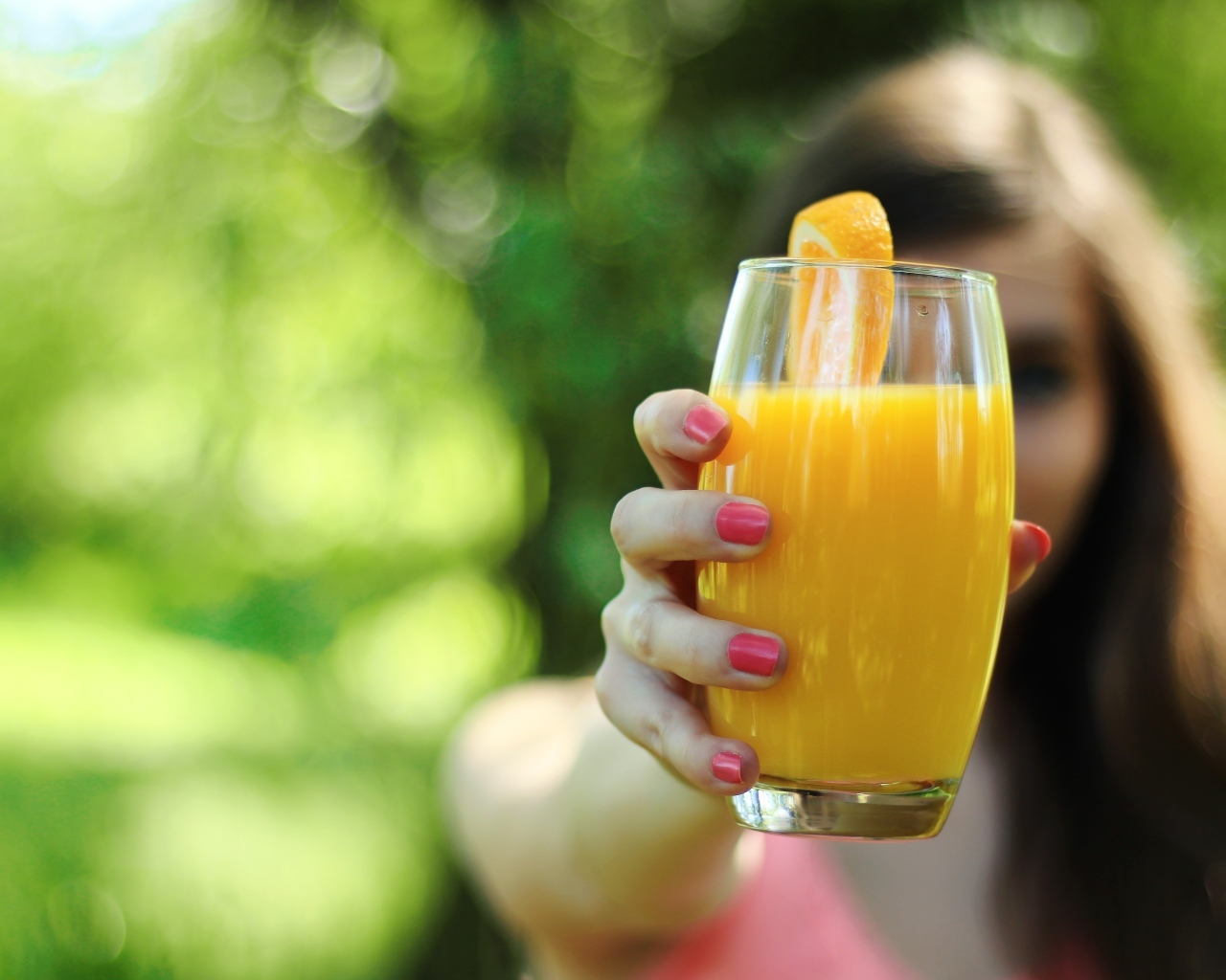 Девушка держит стакан апельсинового сока в руке