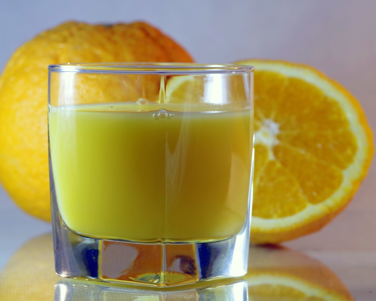 Оранжевый апельсиновый сок в стакане на столе с плодами
