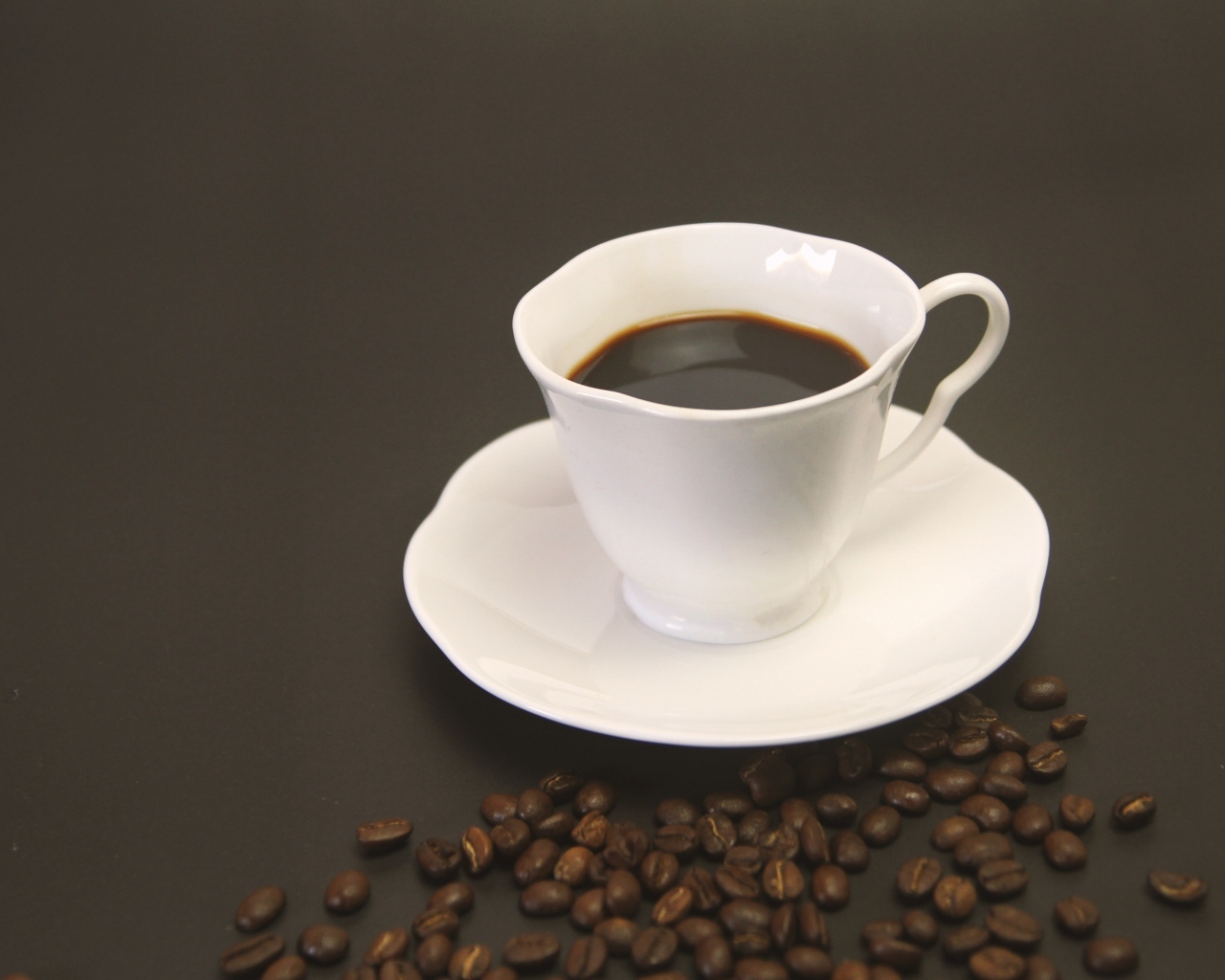 Белая чашка с кофе на столе с зернами