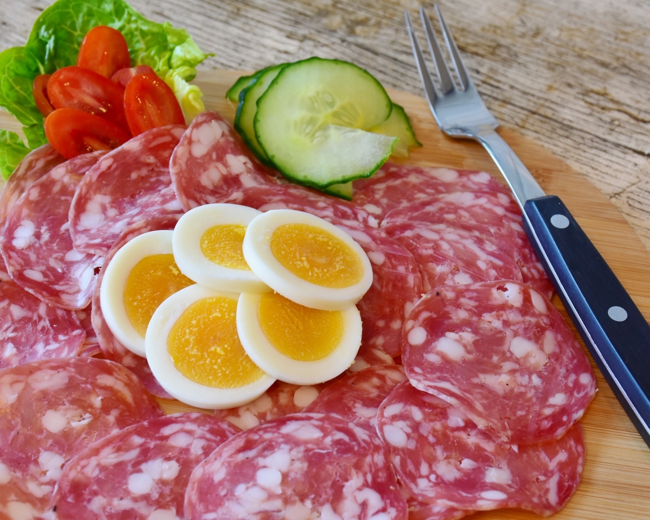 Колбаса салями на доске с вареными яйцами и овощами