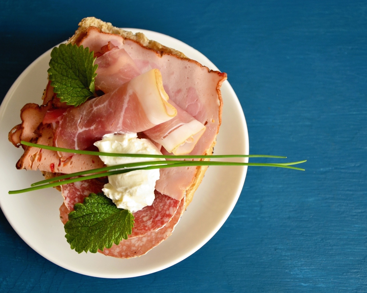 Бутерброд с колбасой и беконом на синем столе