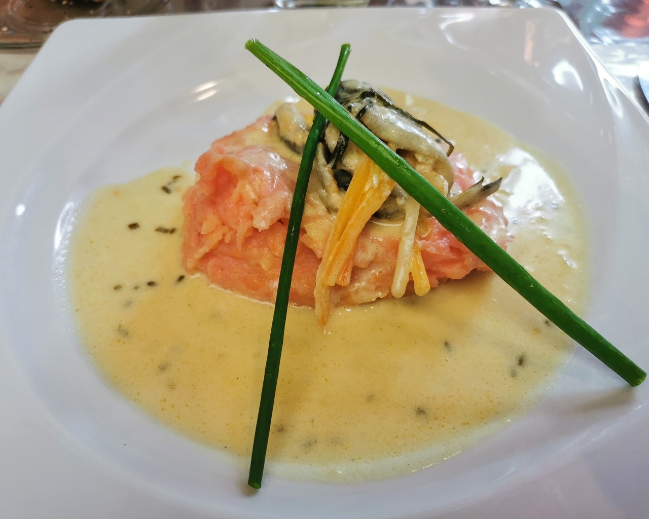 Красная рыба с соусом на тарелке с зеленым луком