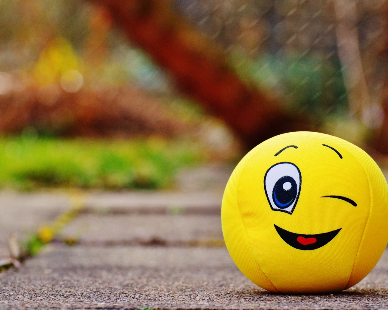 Желтый мягкий мяч смайл на дороге