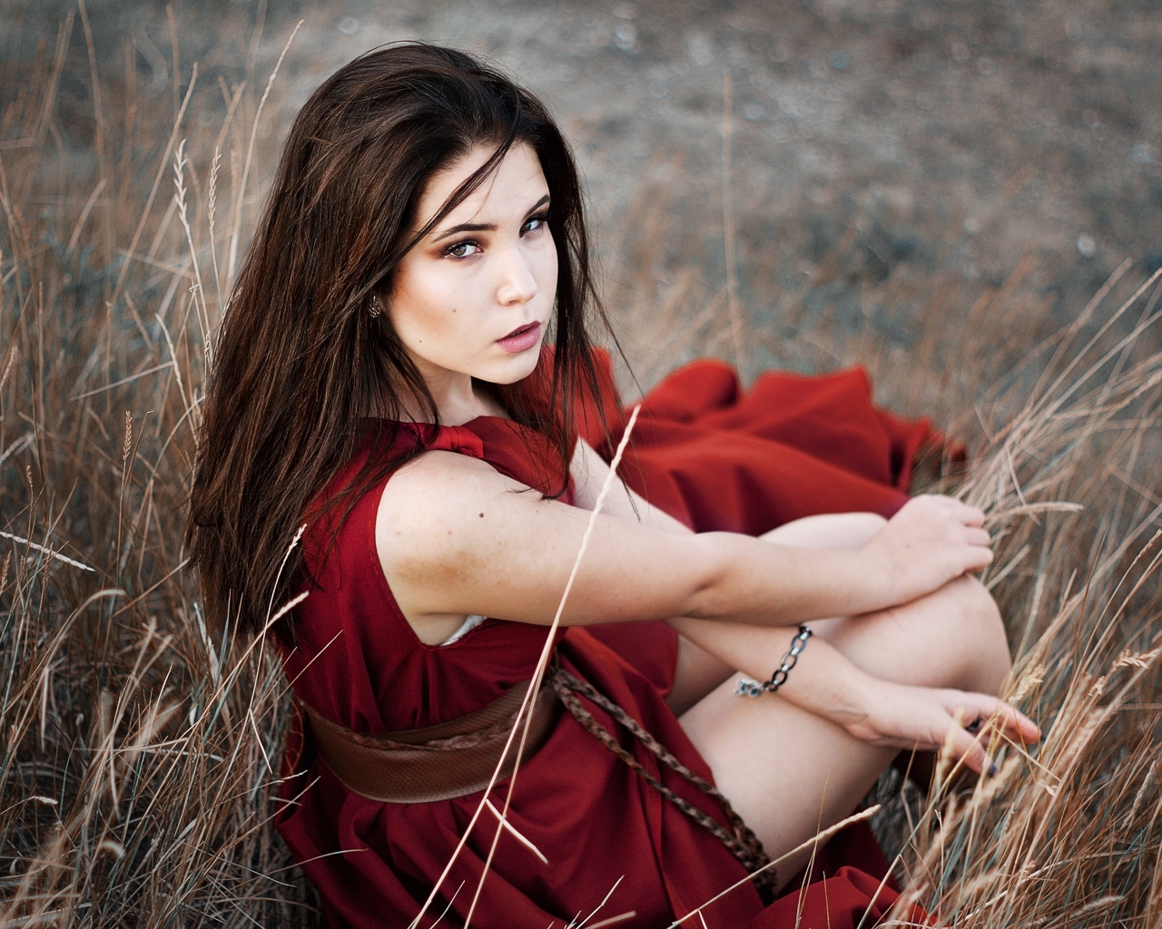 Девушка в красном платье сидит в траве