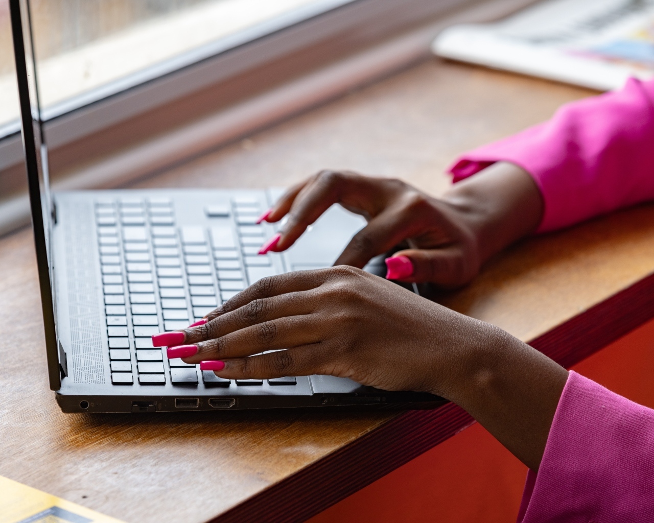Девушка с розовым маникюром сидит за ноутбуком