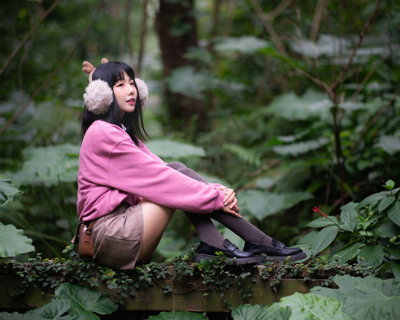 Девушка азиатка в розовом наряде сидит в зарослях