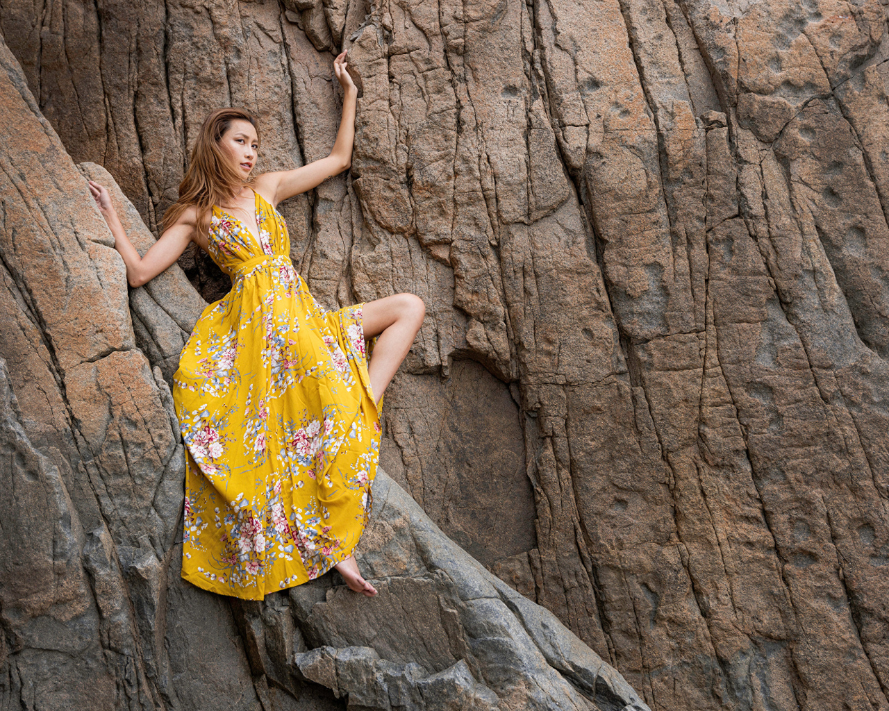 Девушка азиатка в красивом длинном платье позирует на скале