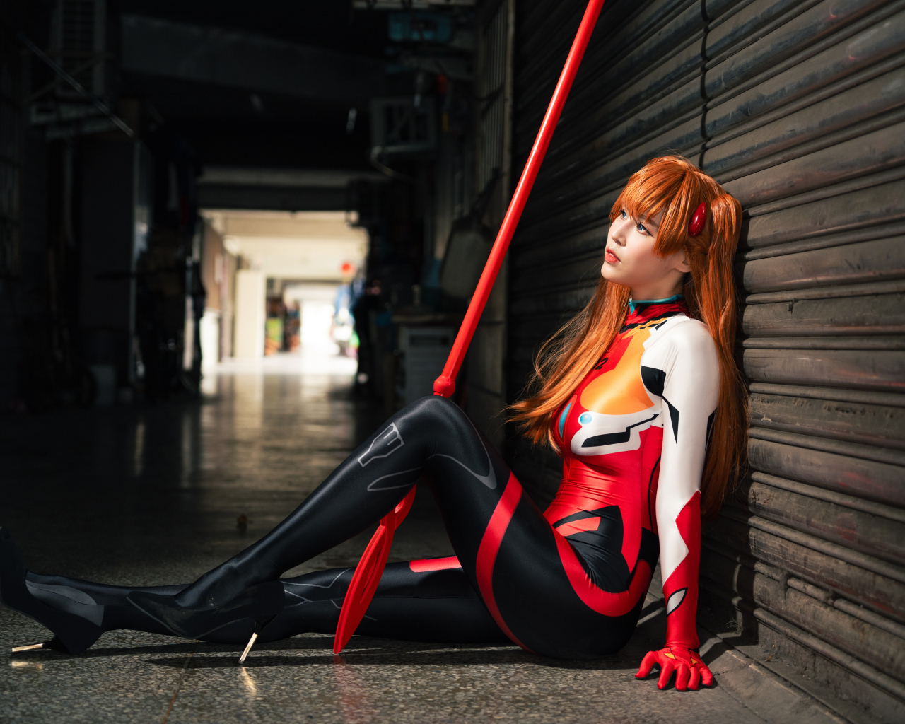 Девушка азиатка в костюме сидит у стены