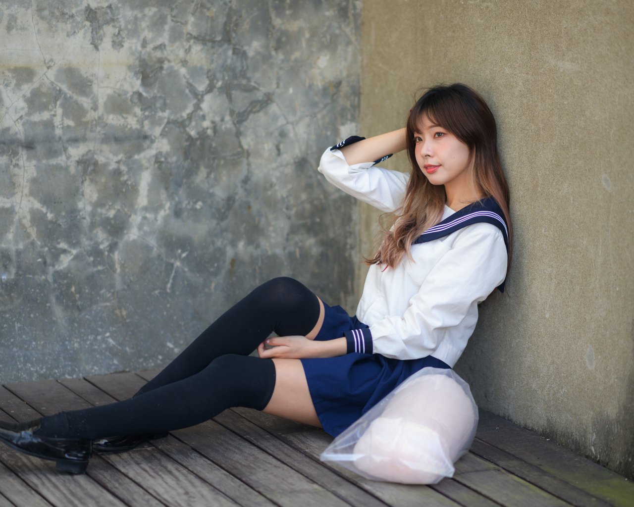 Азиатка в черных чулках сидит у стены