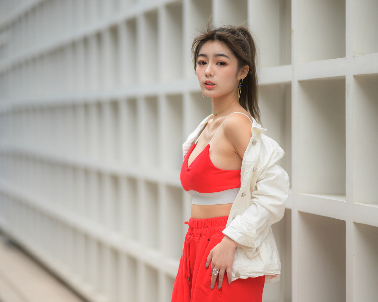 Азиатка в красном спортивном костюме стоит у стены