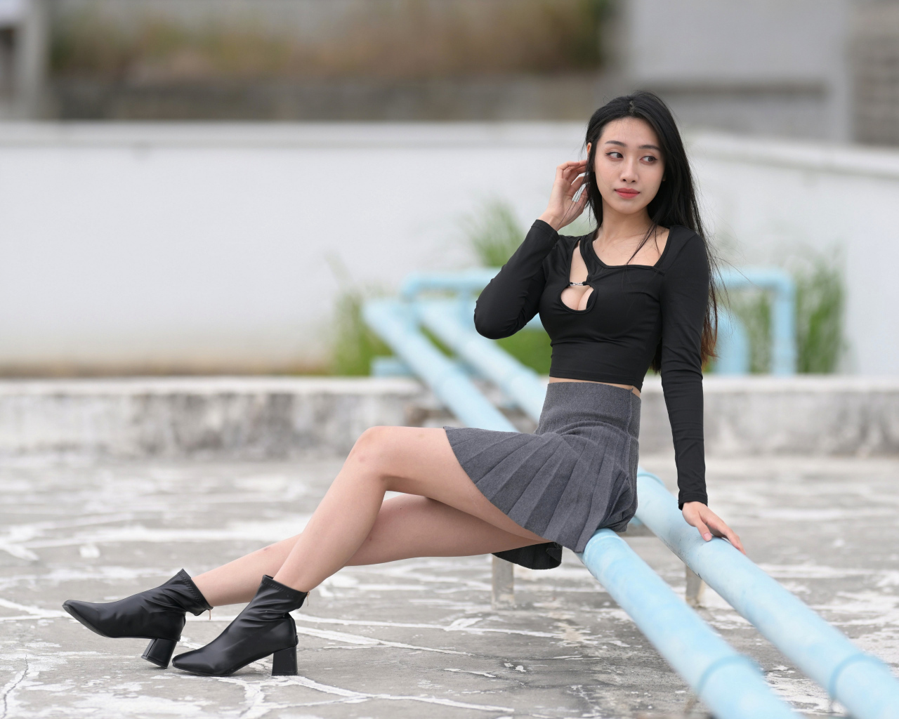 Азиатка в короткой юбке сидит на трубе