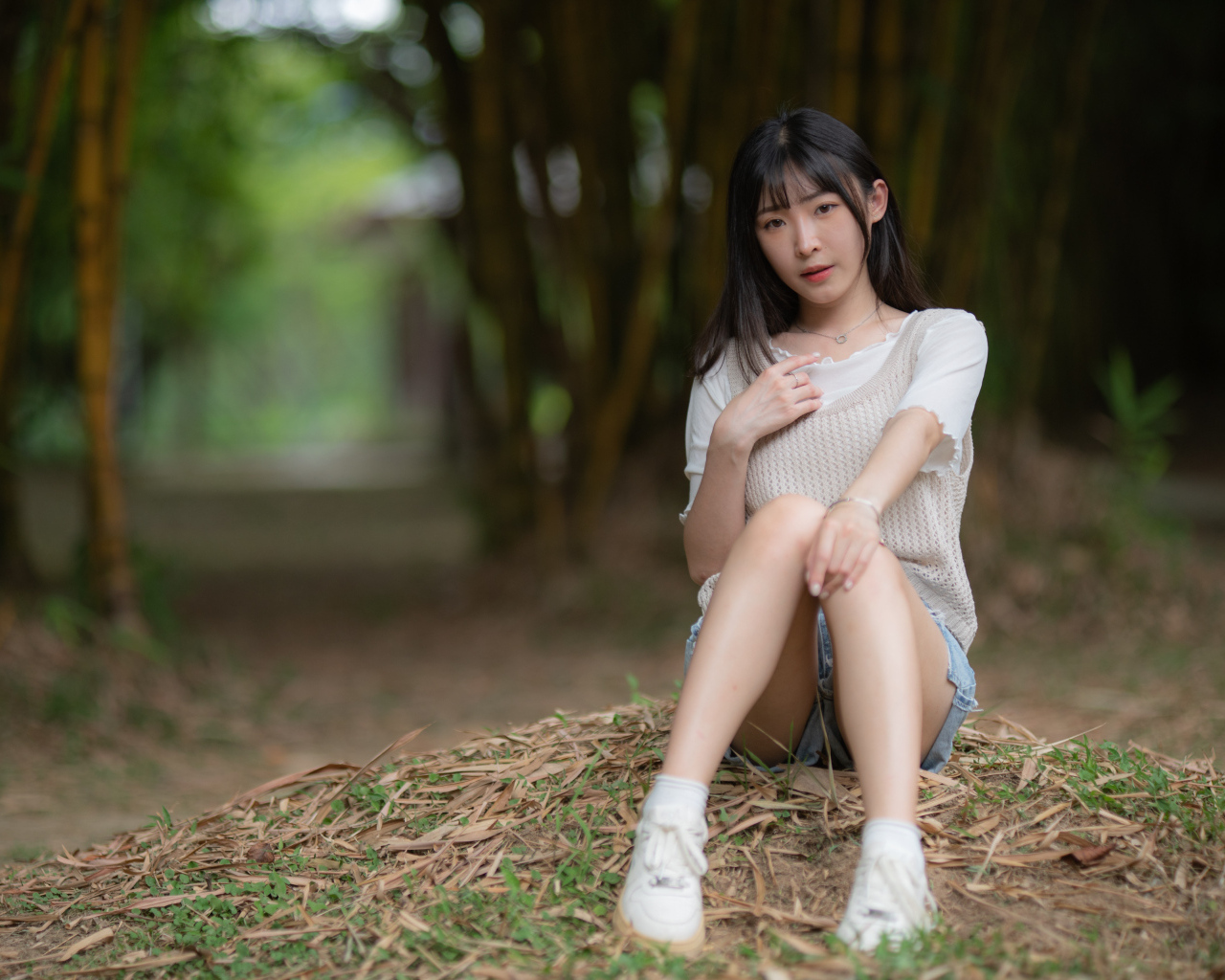 Азиатка сидит на земле в парке