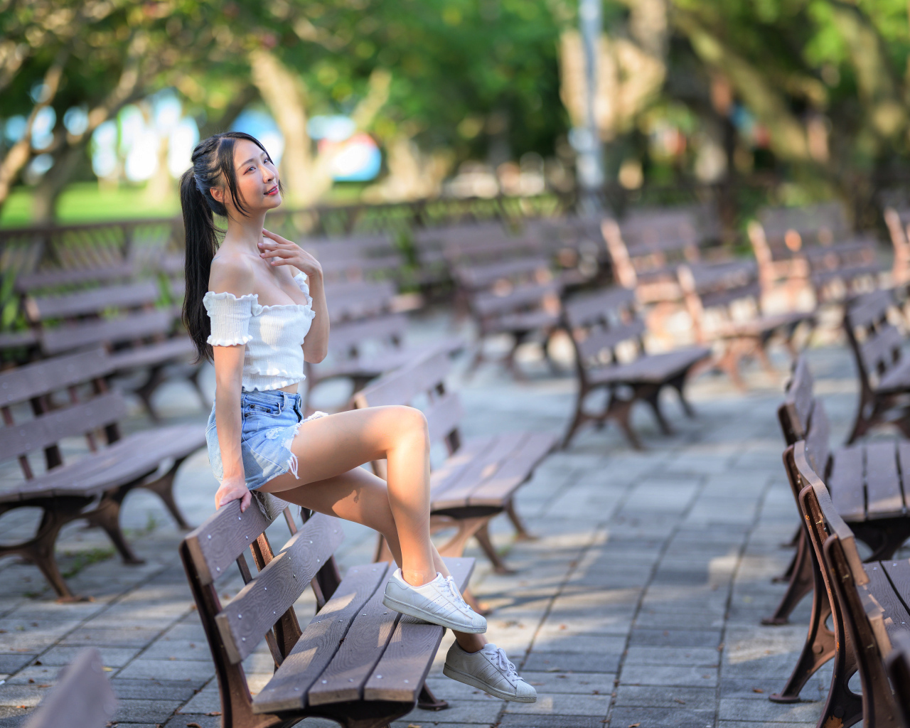 Спортивная азиатка сидит на лавке в парке