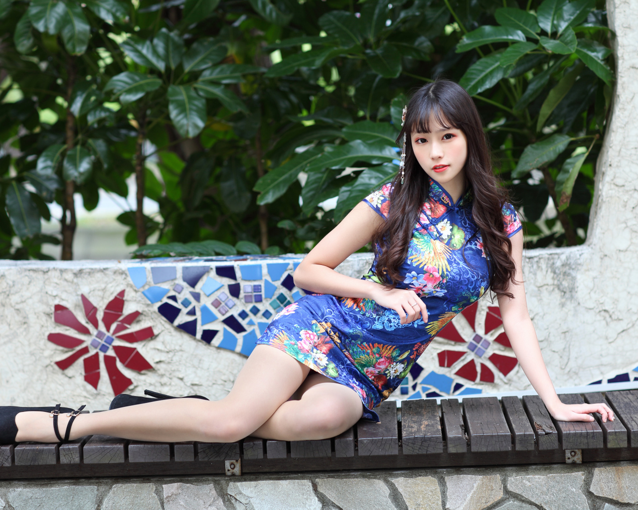 Красивая девушка азиатка в платье лежит на лавке