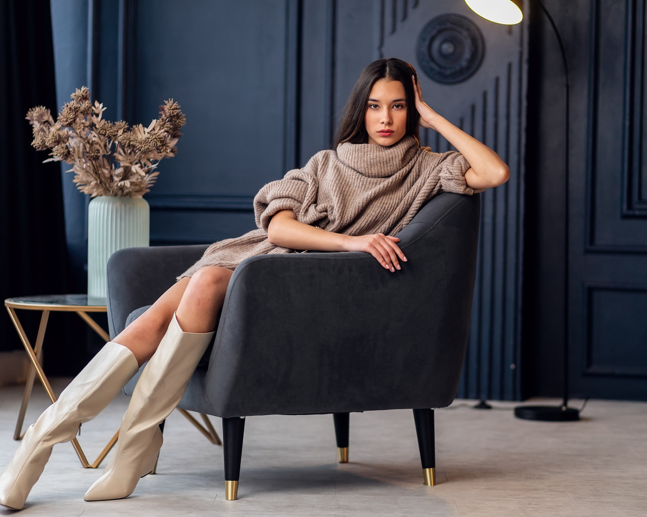 Красивая брюнетка в сапогах сидит в кресле