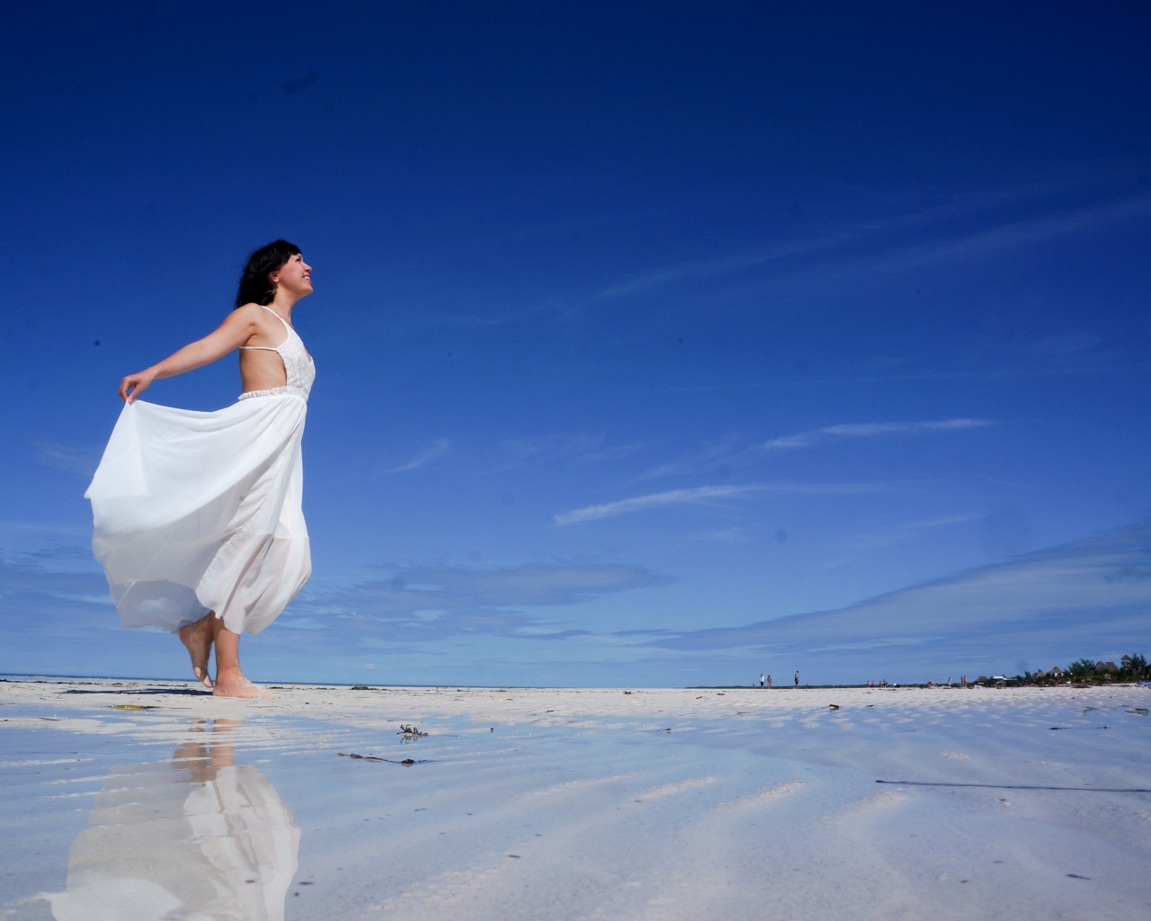 Красивая девушка в белом платье на мокром песке