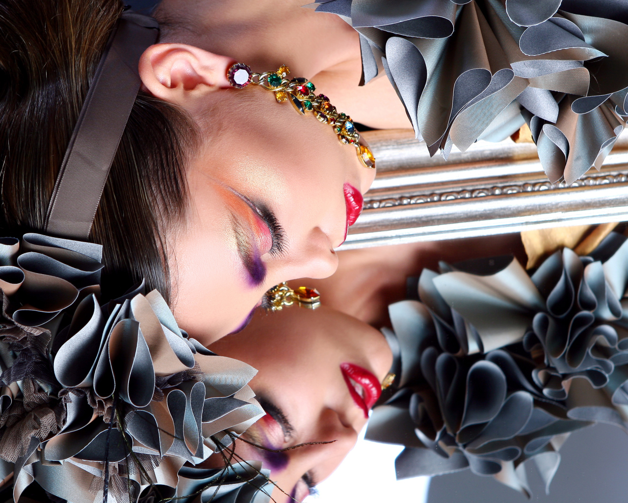 Красивая девушка с ярким макияжем отражается в зеркале