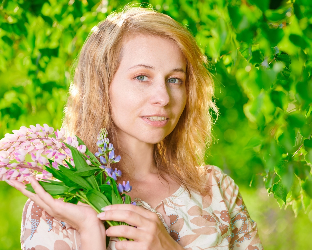 Красивая девушка с цветами люпина в руке