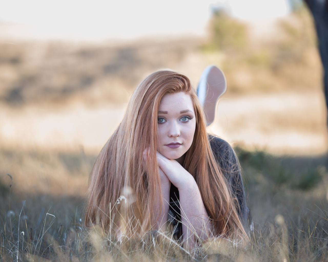 Красивая рыжеволосая девушка лежит на траве