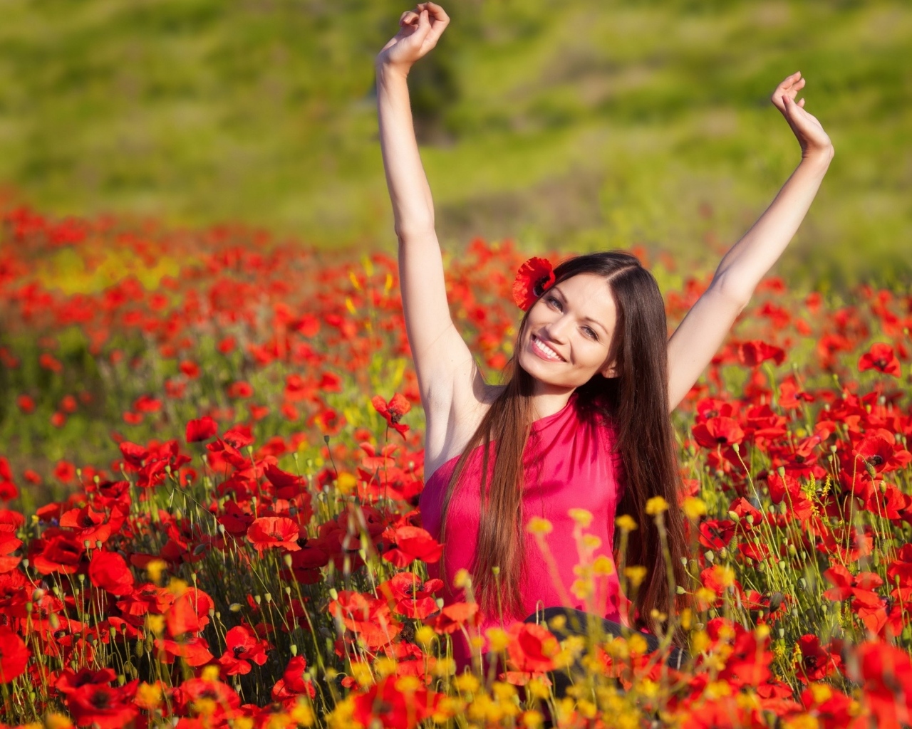 Красивая улыбающаяся девушка на поле с красными маками