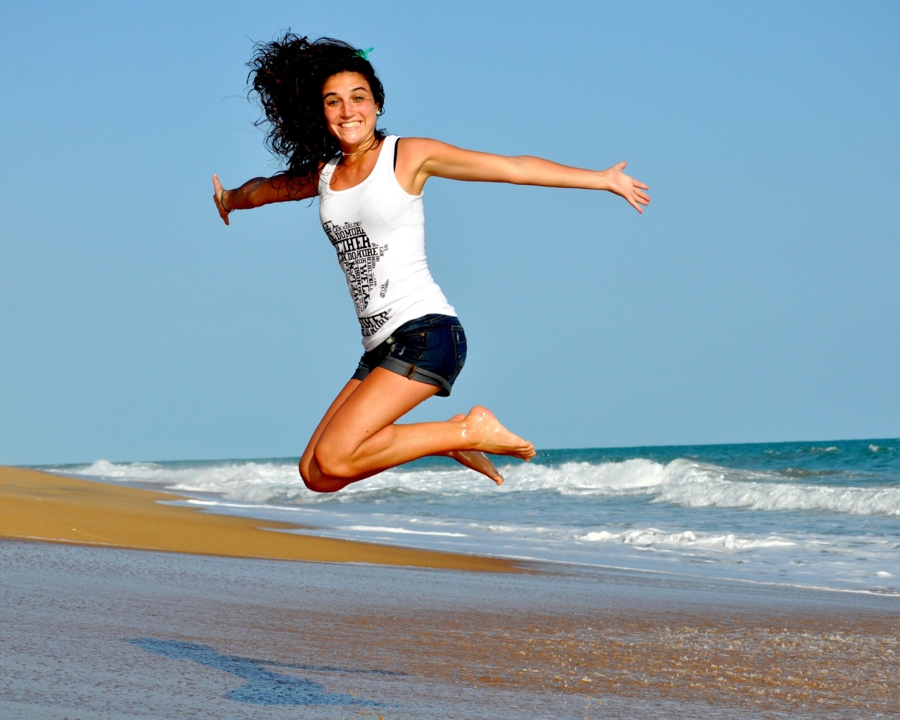 Веселая девушка прыгает на морском берегу