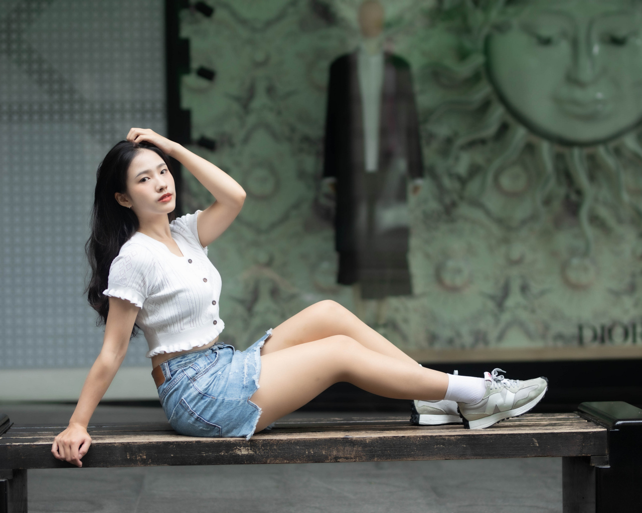 Милая девушка азиатка в белой кофте лежит на лавке