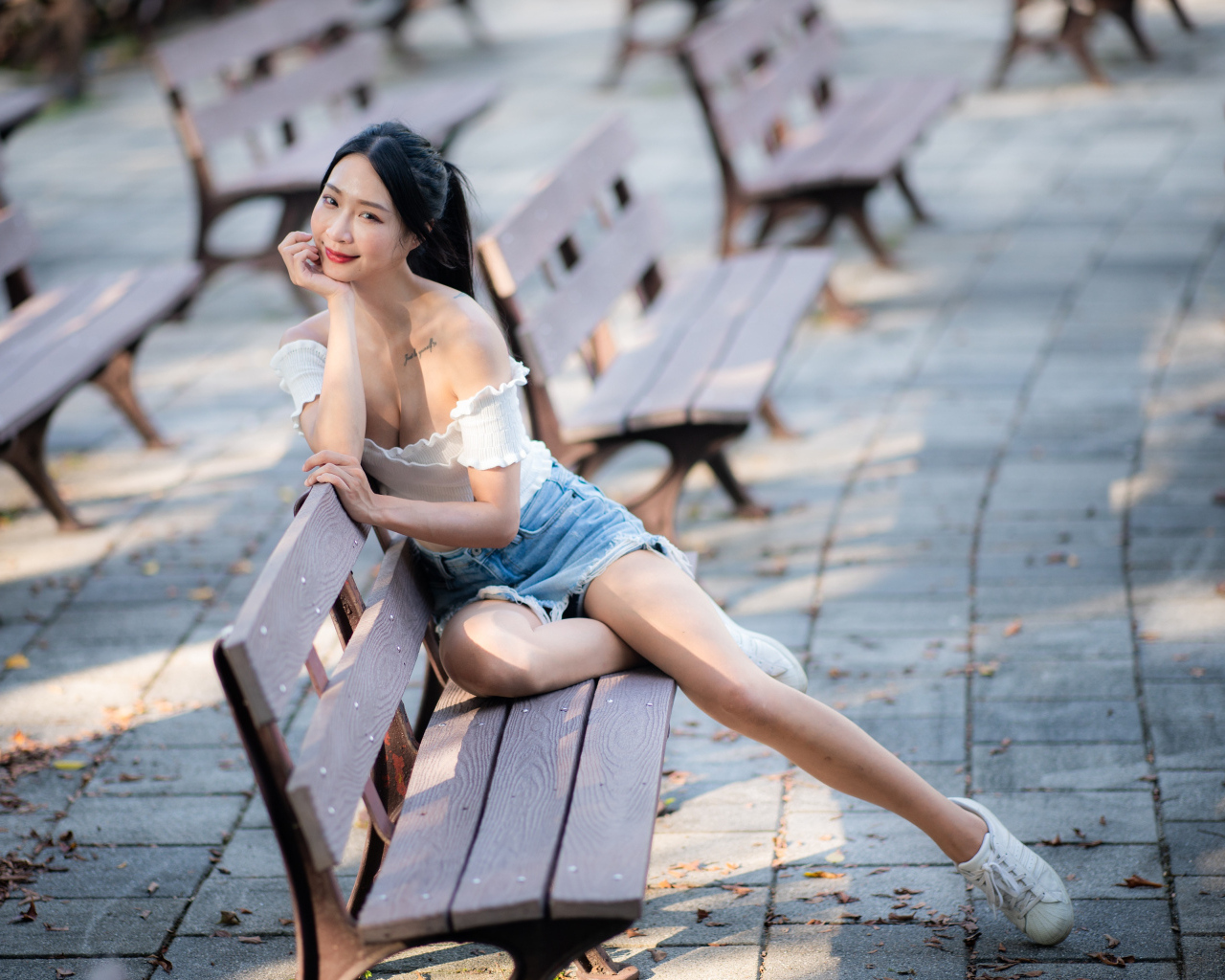 Милая девушка азиатка сидит на лавке в парке