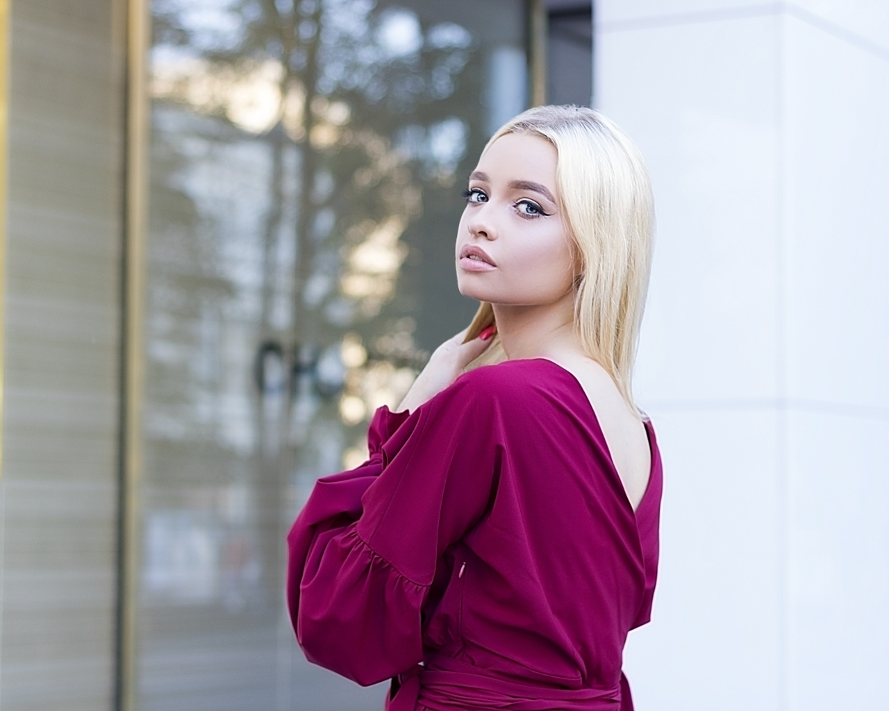 Милая девушка блондинка в платье стоит у здания