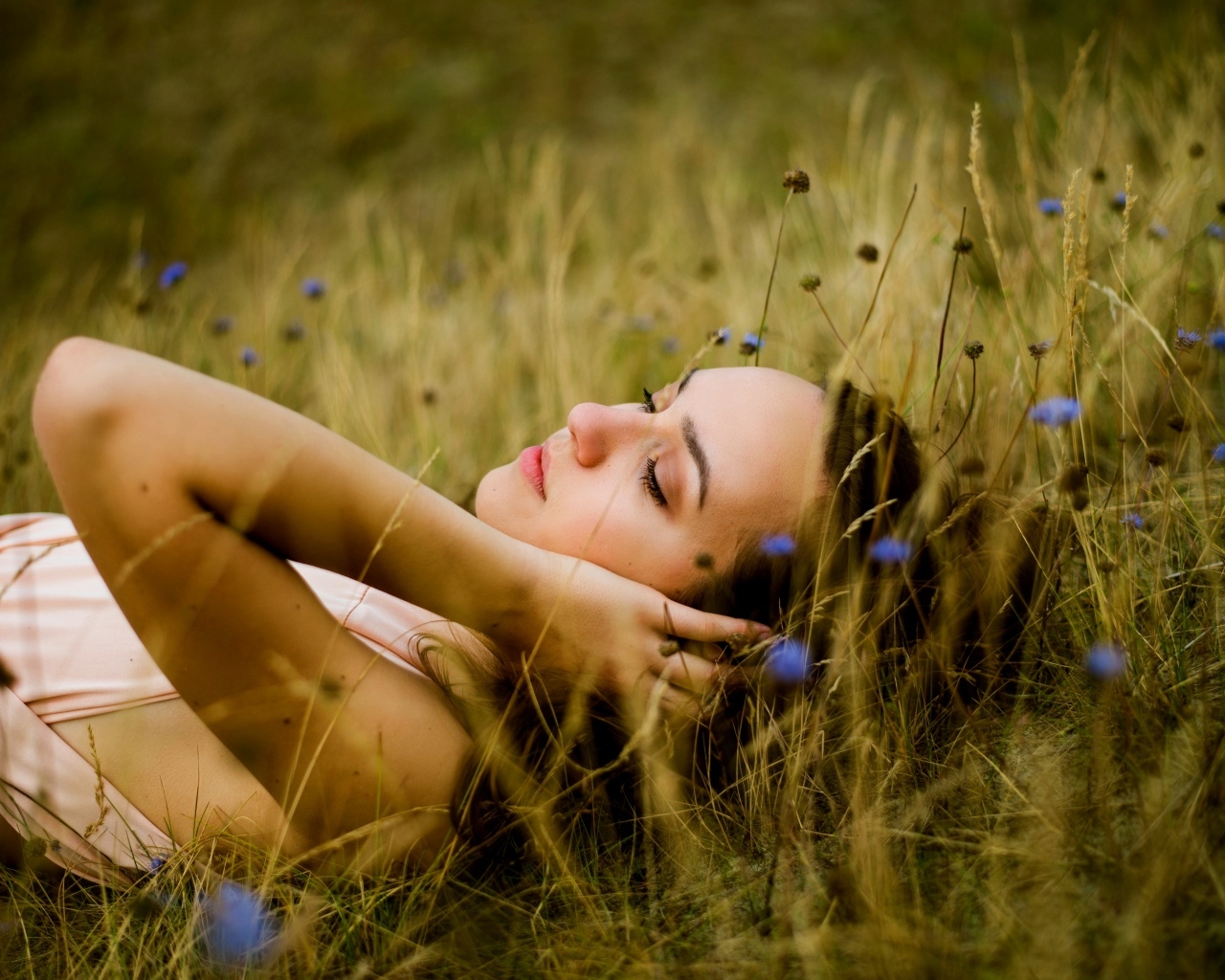 Милая девушка лежит на траве на поле