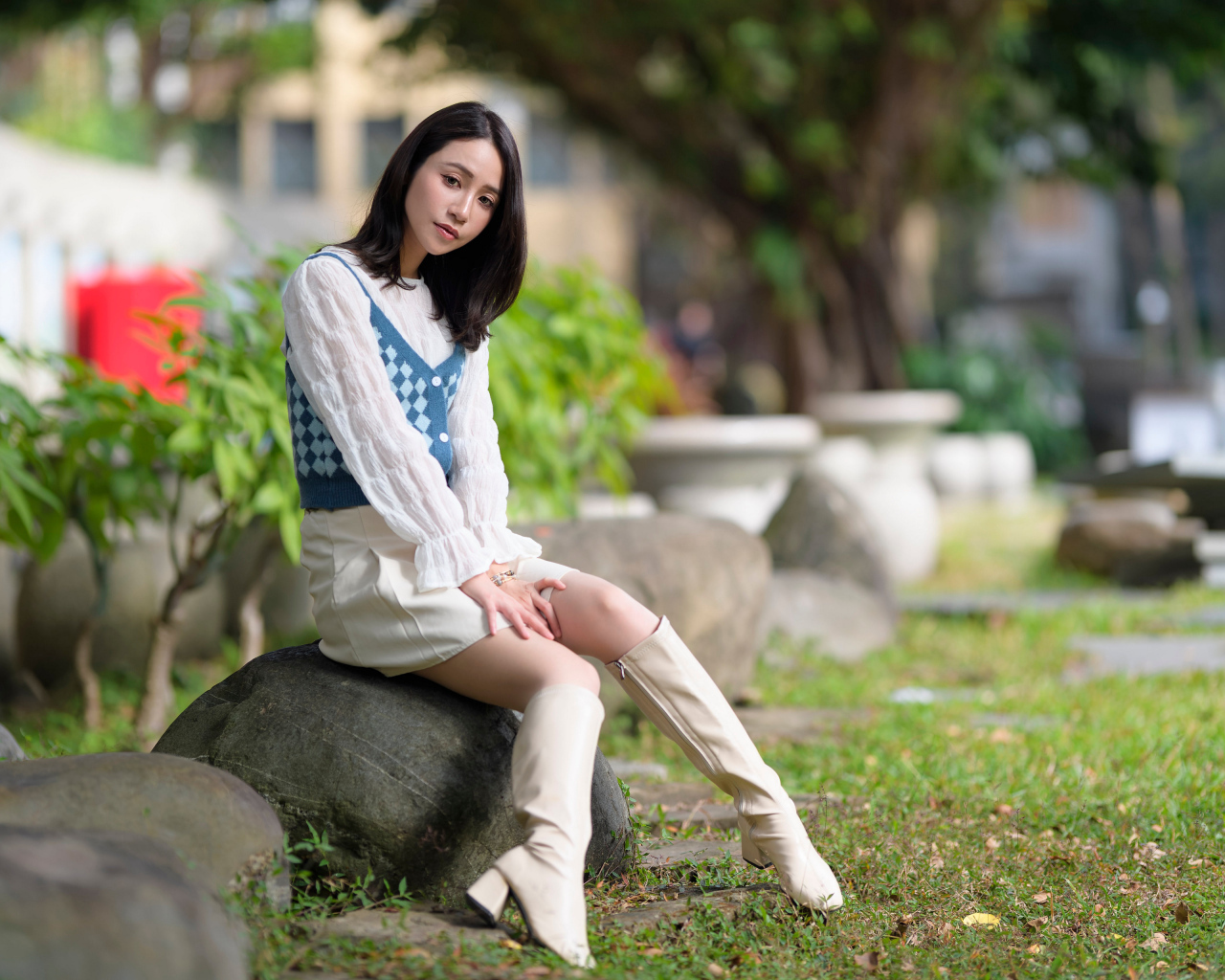 Милая девушка сидит на камне в парке