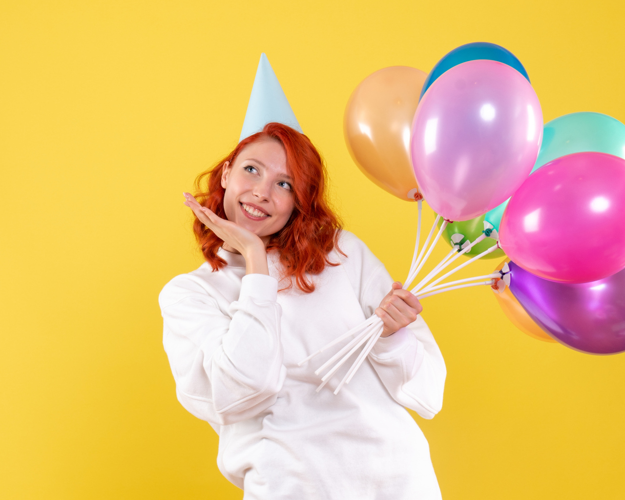 Милая рыжеволосая девушка с шариками на желтом фоне