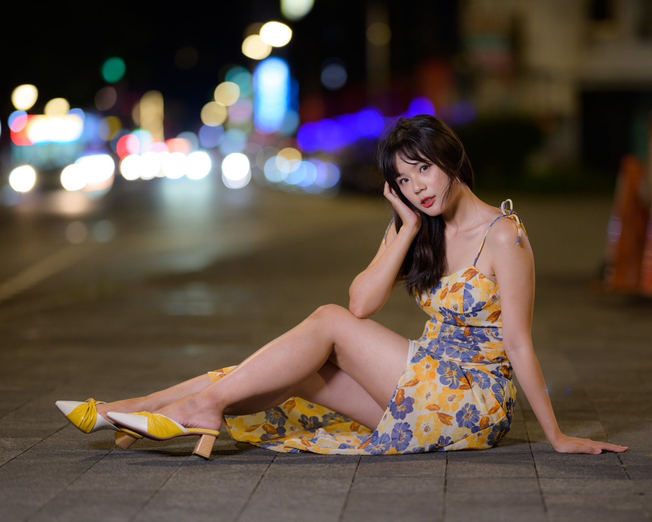 Милая нежная азиатка в платье сидит на дороге